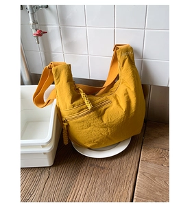Detail view of ginger yellow nylon moon bag with brand embroidery and woven zipper pull