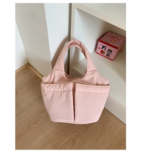 Close-up of pink quilted puffy tote bag featuring front dual pockets and padded handles