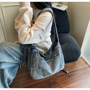 Detailed view of spacious snow-wash denim tote bag worn by a model on a chair
