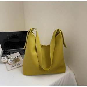 Detail of bright yellow lychee leather Hobo bag with silver buckle on a white desk