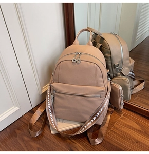 Detail view of beige lychee texture backpack with metallic zippers and side pouch