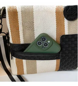 Detail of exterior zipper pocket on striped canvas travel bag with a phone inside