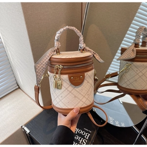 Detailed view of white quilted bucket bag with leather trim and decorative silk scarf handle