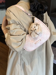 Pink checkered half-moon shoulder bag with a cute plush rabbit charm on a stylish model