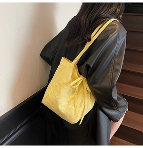Close-up of yellow canvas tote bag with Rise and Shine print and bow strap detail