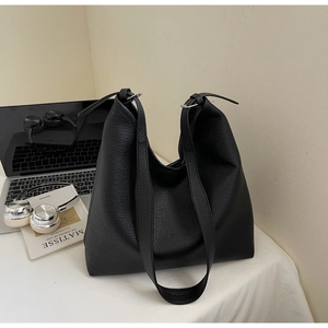 Detail view of black pebbled leather tote bag with soft texture and single shoulder strap