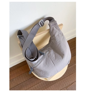 Detail view of the gray nylon dumpling bag featuring the WGDORA logo on the adjustable strap