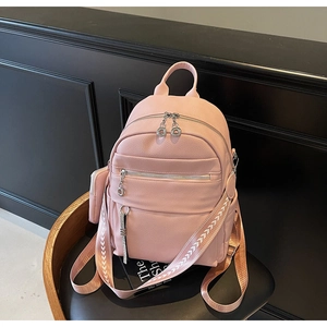 Detailed close-up of pink pebbled faux leather backpack with silver hardware and strap