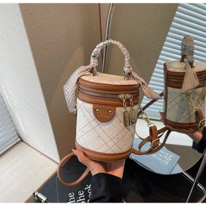 Detail of beige quilted bucket bag with silk scarf handle and brand metal logo