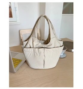 Detail view of multi-pocket canvas bucket bag on a minimalist desk with laptop and coffee