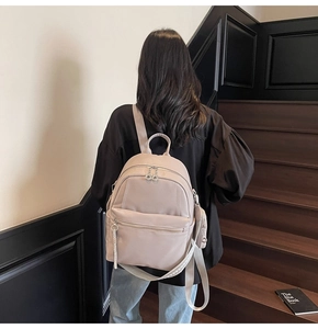 Detailed macro view of beige lychee leather texture and silver zipper on backpack