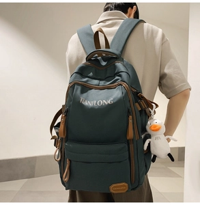 Detail of dark green canvas backpack with brown leather pulls and duck pendant