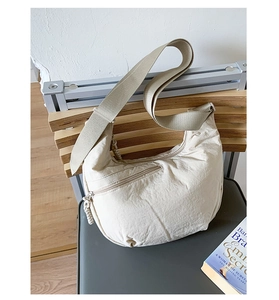 Detail of beige nylon crescent bag featuring smooth metal zippers and wide fabric strap