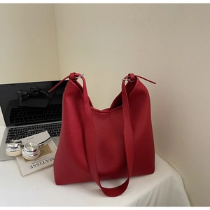 Detailed close-up of a red litchi grain leather tote bag on a minimalist desk