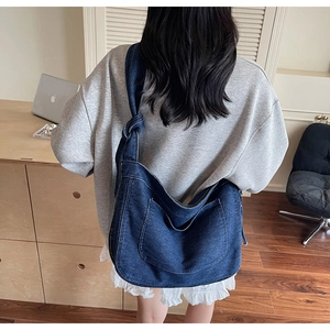 Detail of a large denim tote bag featuring a handcrafted knot shoulder strap design
