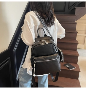 Black pebbled leather backpack with decorative woven strap shown on a model