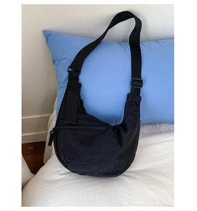 Close-up of black Baggu crescent bag on white bedding showing fabric texture and logo