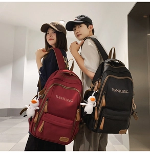 Detail of burgundy and black backpacks with Tianflong logo and duckling charms