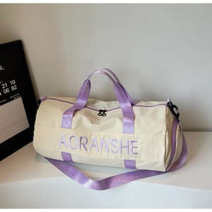 Detail of cream travel bag with purple straps showing durable nylon fabric and embroidery