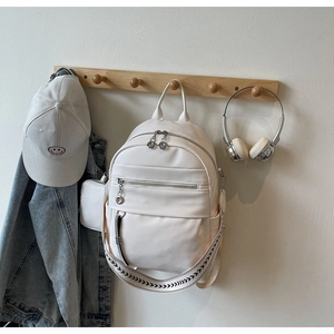 Detail of white pebbled leather backpack with a geometric pattern wide strap and side pouch