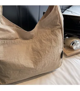 Close-up of beige tote bag showing fine pleated texture and large exterior pocket