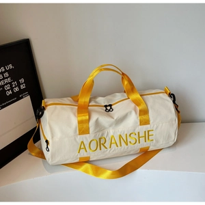 Detail view of cream canvas travel bag with bright yellow handles and embroidery