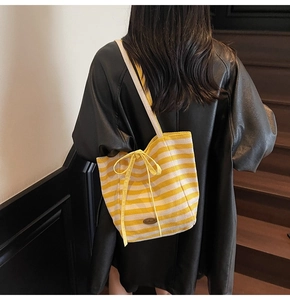 Detail of yellow and beige striped canvas tote bag with a bow and shoulder strap