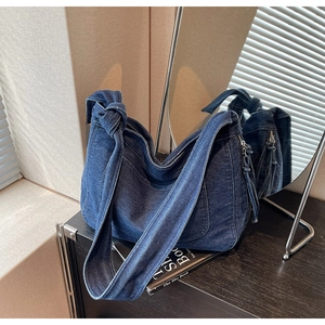 Detail of vintage blue denim tote bag featuring knotted strap and washed texture fabric