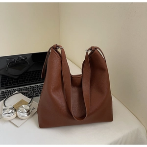 Close-up of brown pebbled leather tote bag detailing wide straps and metal ring connector