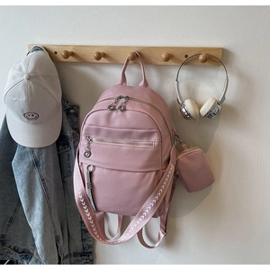 Detail of pink faux leather backpack with arrow pattern straps and small charm pouch