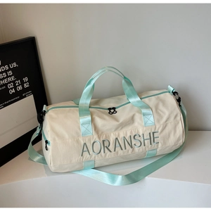 Detail view of the embroidered AORANSHE logo and mint green straps on the cream travel bag