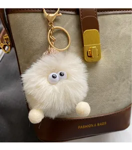 Gros plan d'un pompon blanc duveteux avec yeux sur un sac à main en cuir marron