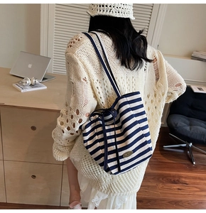 Detailed close-up of blue and white striped canvas tote with handmade metal logo plate