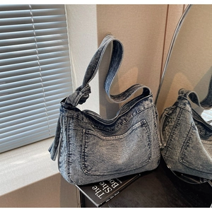 Detailed view of washed blue denim tote bag with visible outer pocket and knot shoulder strap