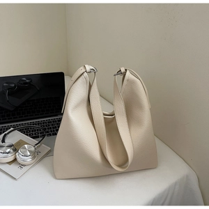 Close-up of beige litchi pattern tote bag with silver buckle in a modern office setup