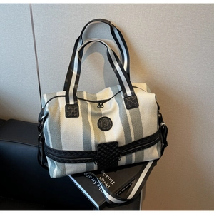Detail of striped travel tote bag with adjustable shoulder strap and woven handles