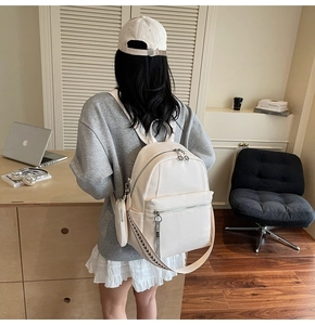 White pebbled leather backpack detail with striped woven strap and small side pouch
