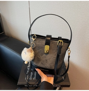 Détail du sac seau en toile grise avec lanières en cuir noir et fermoir en métal doré