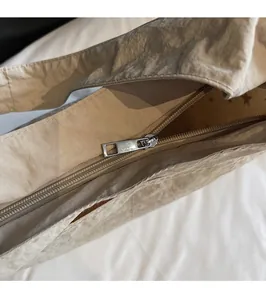 Close-up of smooth silver metal zipper on beige pleated tote bag with star print lining