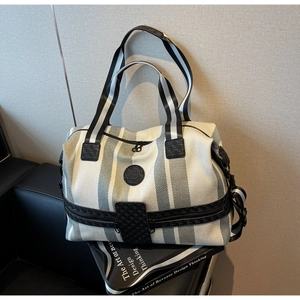 Macro shot of striped canvas travel bag with leather patch and wide woven shoulder strap