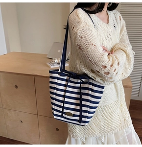 Blue and white striped canvas tote with ribbon bow detail and gold metal label
