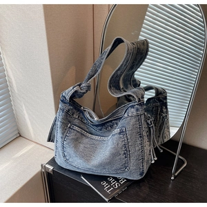 Detail of vintage denim tote bag with knot strap design and decorative tassel accent