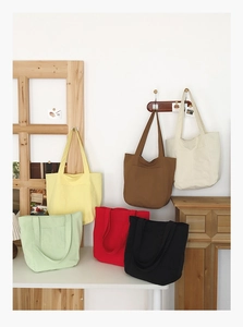 Detailed macro view showing six colorful canvas tote bags in a cozy home setting