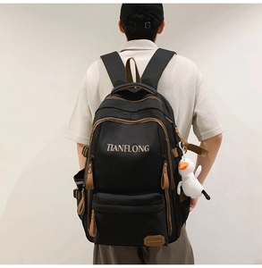 Detail of minimalist black laptop backpack with brown zipper accents and plush duck charm