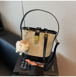 Détail du sac seau en toile avec bordure en cuir noir et breloque monstre en peluche