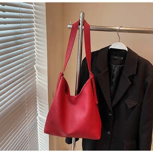 Macro detail of red lychee grain leather tote bag with wide shoulder strap on hanger