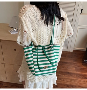 Detail of green and white striped canvas tote with bow tie and handmade metal label