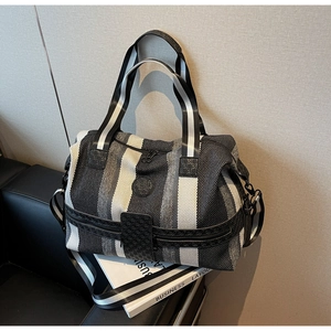 Detailed view of black and white striped knitted travel bag on a leather sofa