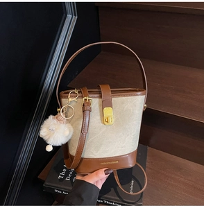 Détail du sac seau rétro en tissu beige avec garniture en cuir brun et fermoir doré