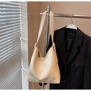 Close-up of cream hobo bag showing pebbled leather texture on a minimalist hanger